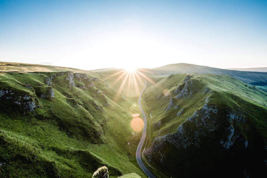 Photo shows a beautiful sunset over a green mountainous region.