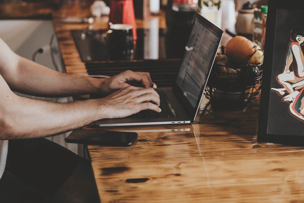 Photograph of man working with innovation mindset on laptop in cafe.