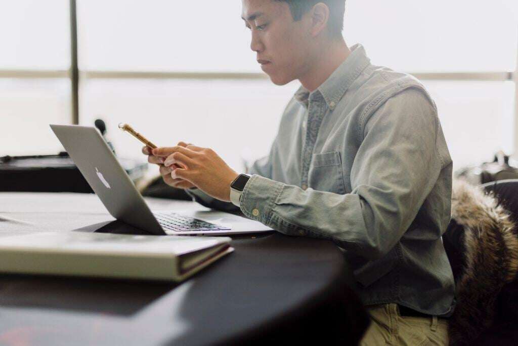 Picture shows a man distracted from his work by his phone.