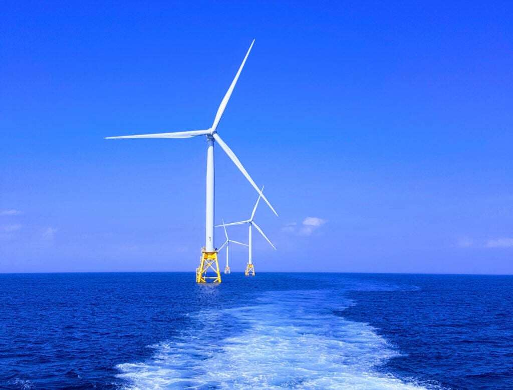 Photo shows wind turbines in the ocean.